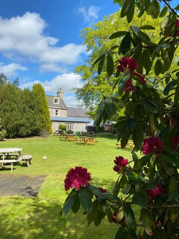 a park with picnic tables and flowers in front of a building at Bennachie Lodge Hotel in Kemnay in Inverurie