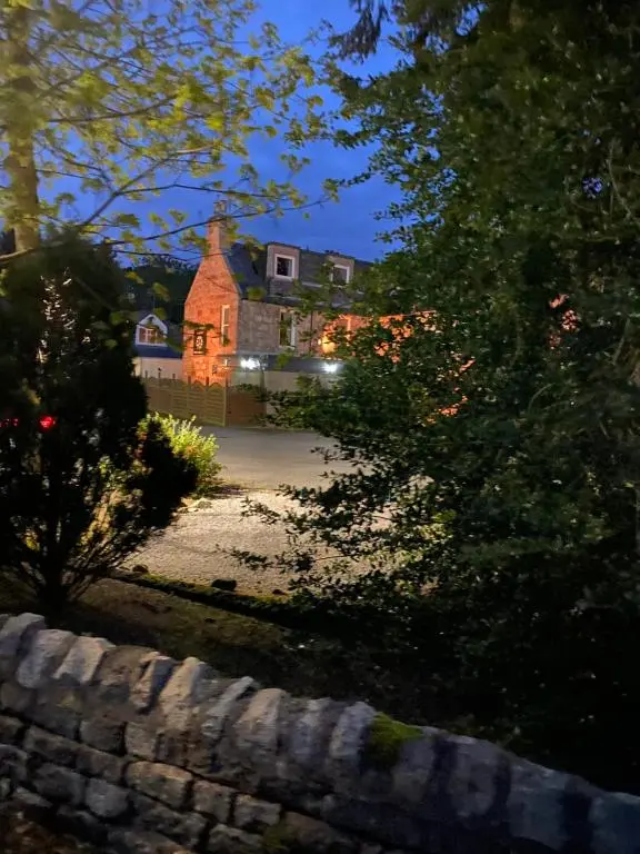 a large house is seen through the trees at Bennachie Lodge Hotel in Kemnay in Inverurie