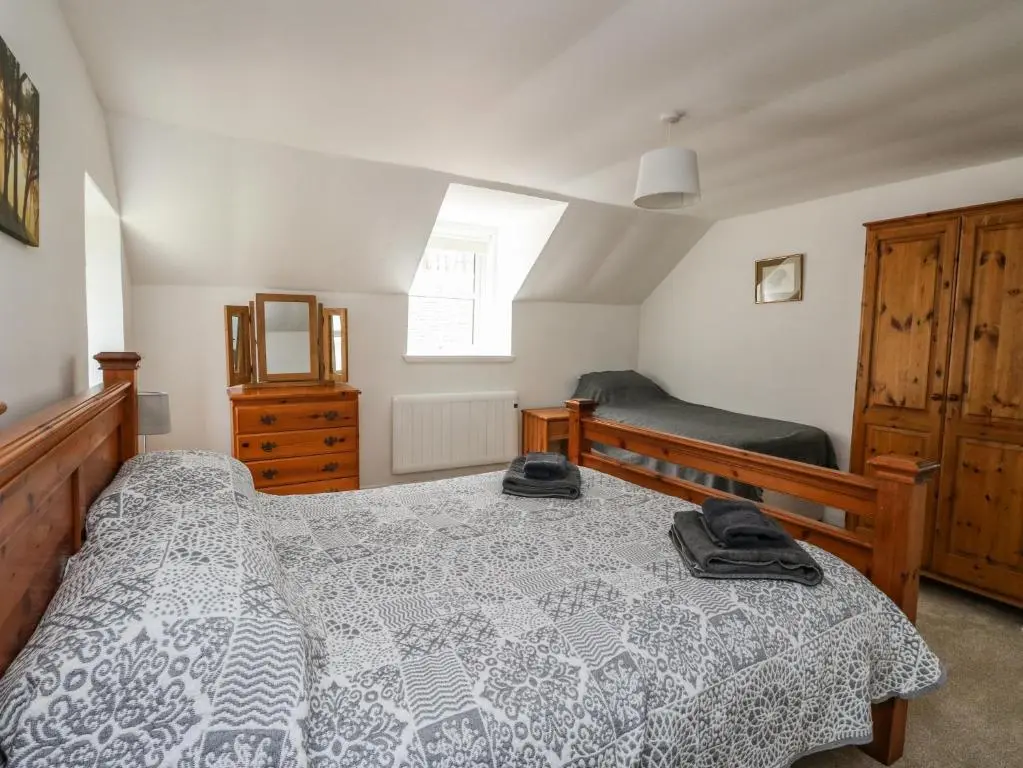 a bedroom with a bed and a dresser at Storkery Cottage in Aberdeen
