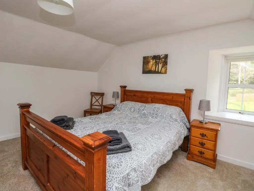 a bedroom with a wooden bed and a window at Storkery Cottage in Aberdeen
