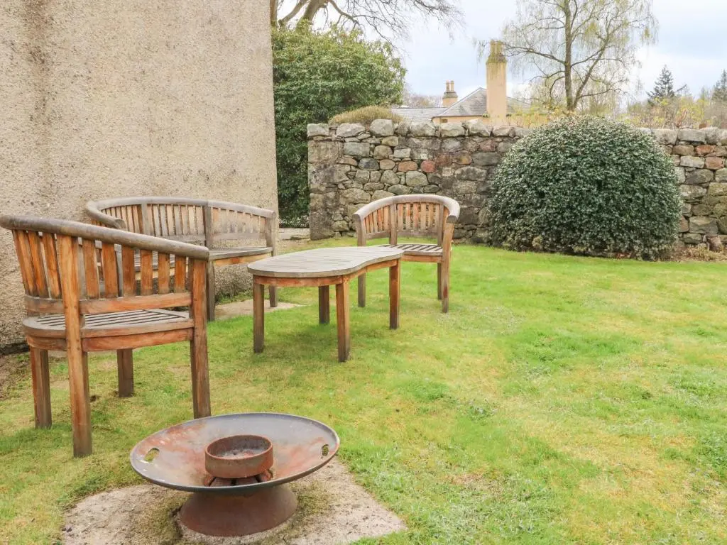 two benches and a bird feeder in a yard at Storkery Cottage in Aberdeen