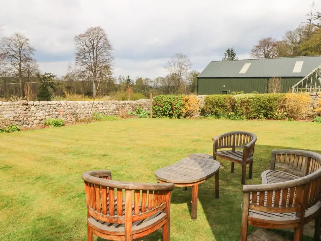 two chairs and a table in a yard at Storkery Cottage in Aberdeen