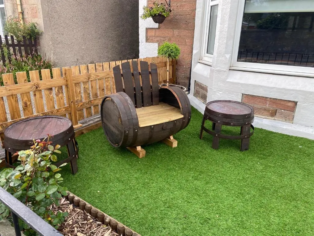 a yard with a wooden chair and two stools at Adrian's Guest House in Inverness