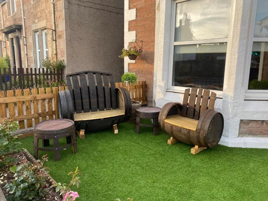 a group of chairs sitting on the grass next to a window at Adrian's Guest House in Inverness