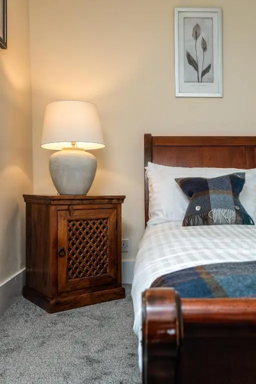 a bedroom with a bed and a lamp on a night stand at The Green Inn Rooms in Ballater