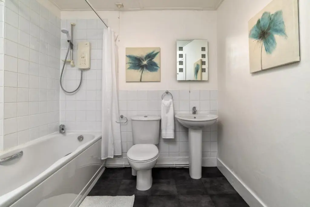 a white bathroom with a toilet and a sink at The Green Inn Rooms in Ballater