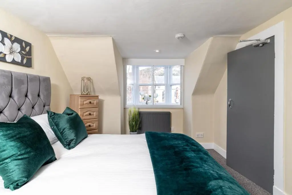 a bedroom with a large bed with green pillows at The Green Inn Rooms in Ballater