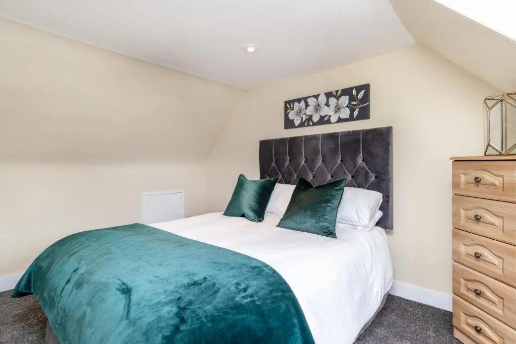 a bedroom with a large bed and a dresser at The Green Inn Rooms in Ballater