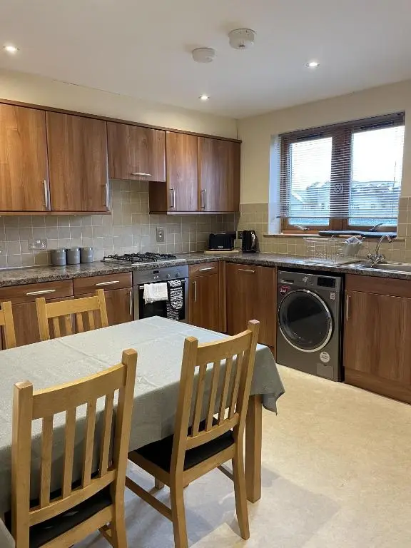a kitchen with a table and chairs and a dishwasher at Waterside View Apartment in Inverness