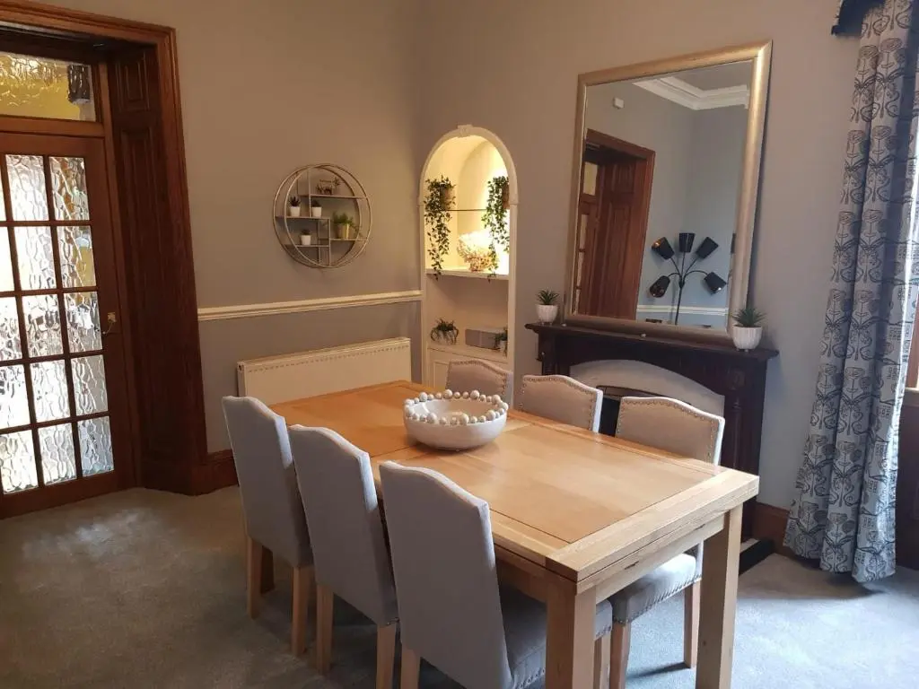 a dining room with a wooden table and chairs at Glencoe House Inverness in Inverness