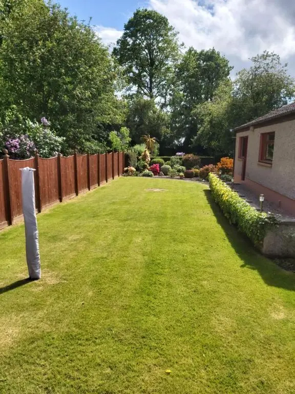 a garden with a fence and a yard at Glencoe House Inverness in Inverness