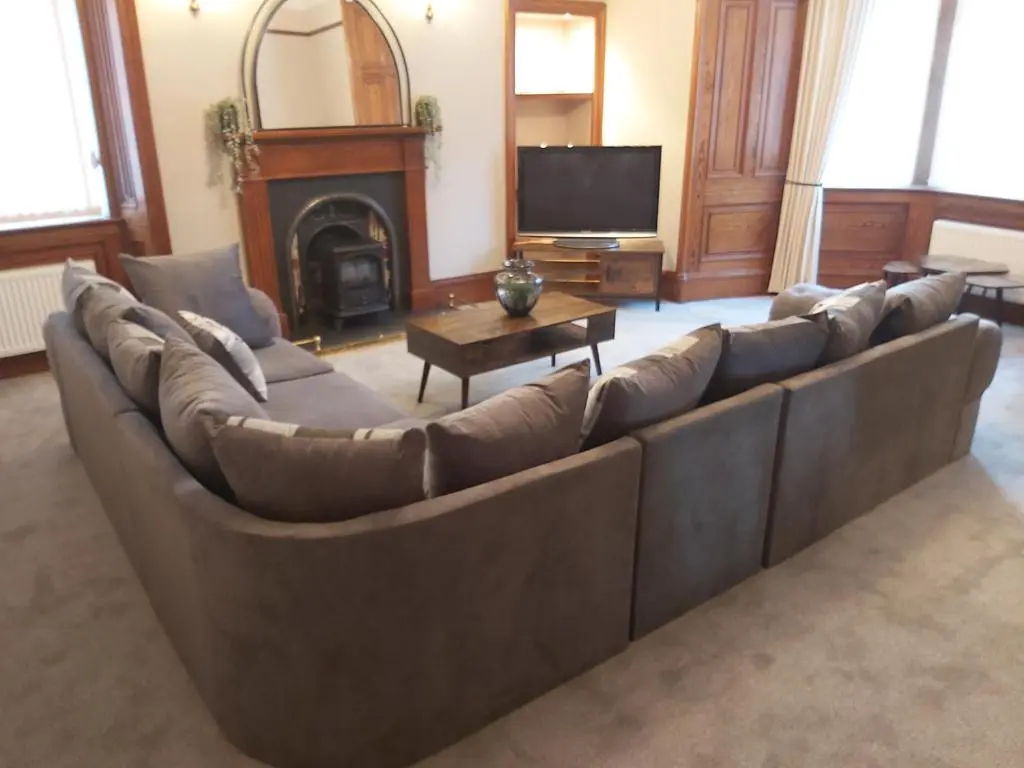 a large couch in a living room with a fireplace at Glencoe House Inverness in Inverness
