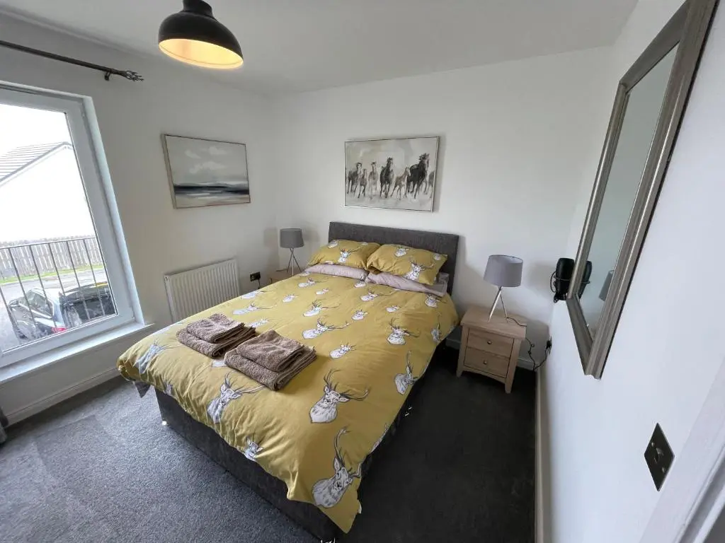 a bedroom with a bed with a yellow comforter at Gorsebank Mews in Inverness