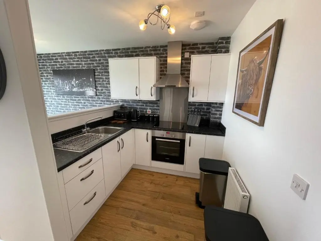 a small kitchen with white cabinets and a sink at Gorsebank Mews in Inverness