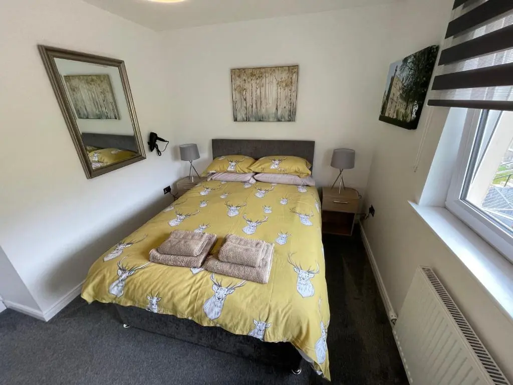 a bedroom with a bed with yellow sheets and towels at Gorsebank Mews in Inverness