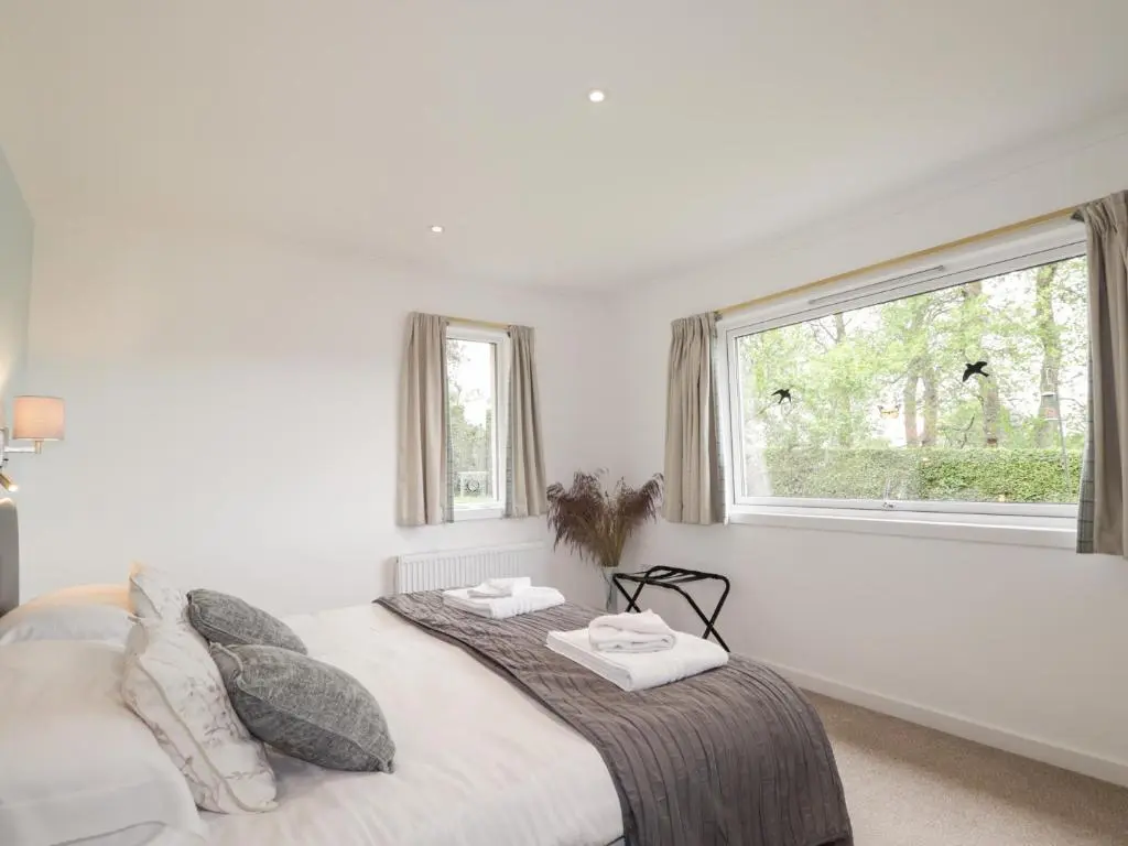 a white bedroom with a bed and a window at Culreach Lodge in Grantown on Spey