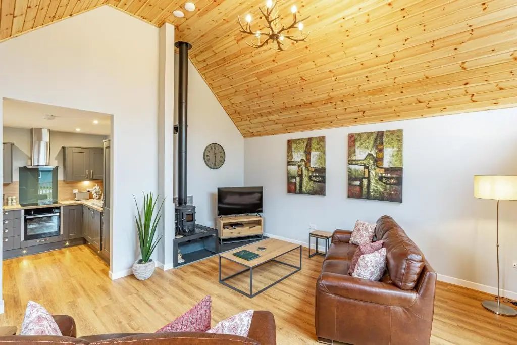 a living room with a couch and a television at Thistle Lodge 21 with Hot Tub in Belladrum