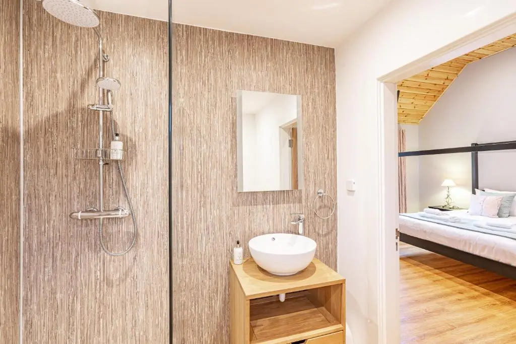 a bathroom with a sink and a shower and a bed at Thistle Lodge 21 with Hot Tub in Belladrum