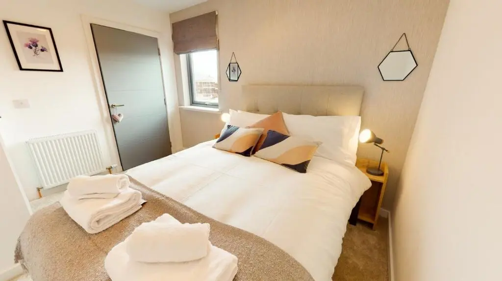a bedroom with a bed with white sheets and pillows at 31 Caledonia Place in Aviemore