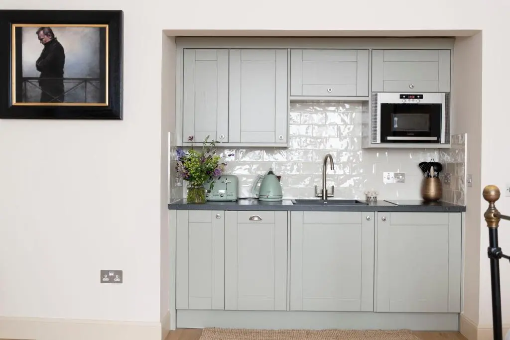a white kitchen with a sink and a microwave at Art House Apartments in Inverness