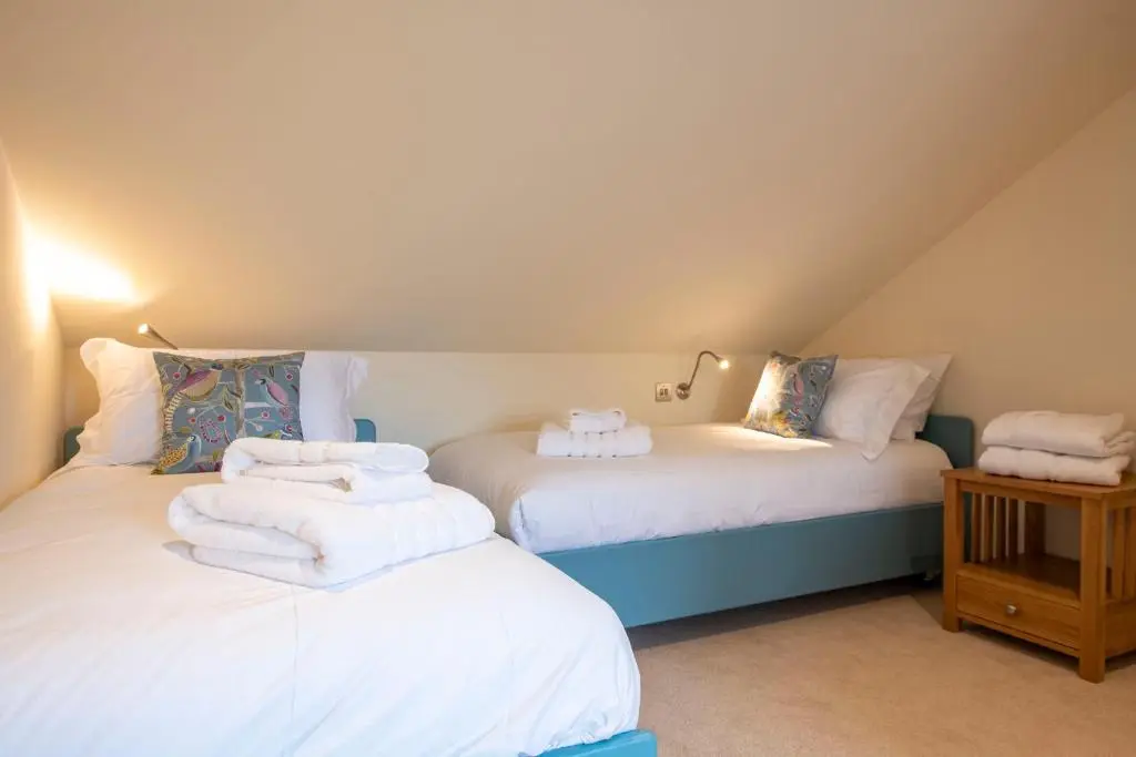 two beds in a attic room with towels on them at Art House Apartments in Inverness