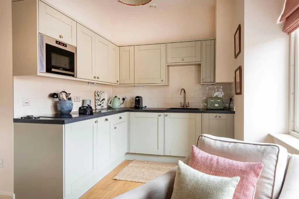 a white kitchen with white cabinets and a couch at Art House Apartments in Inverness
