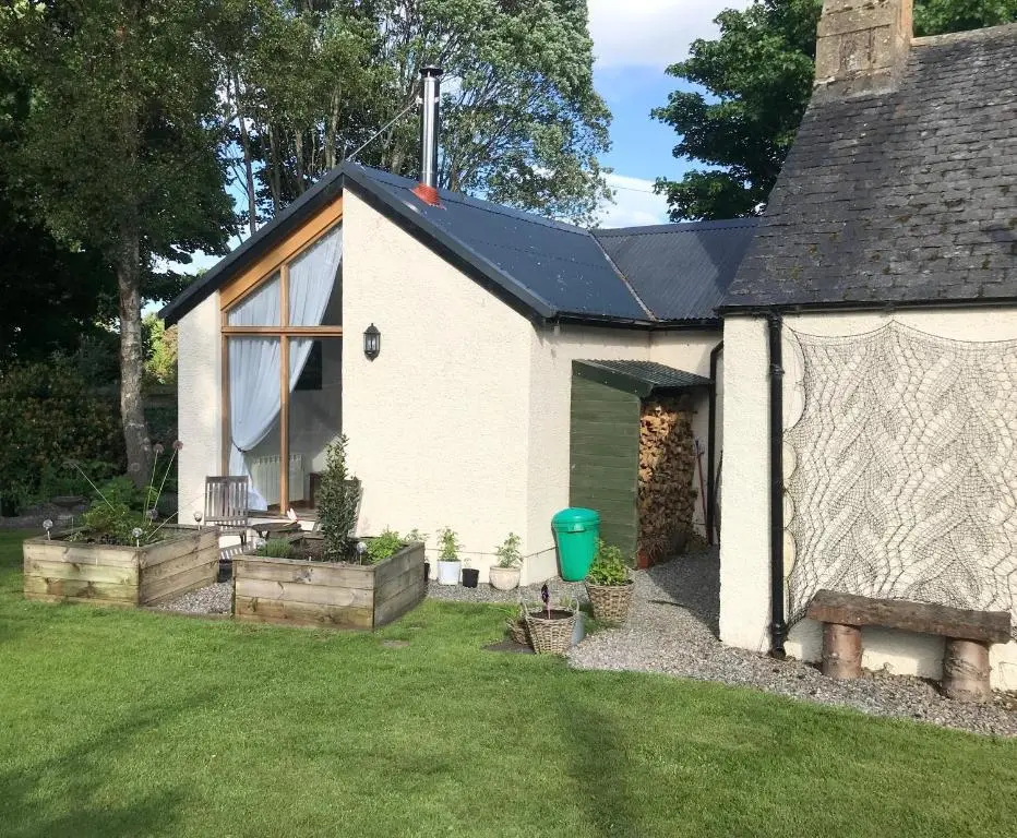 a white house with a green door in a yard at Contemporary One Bedroom Apartment Close To All Amenities In Conservation Area in Tain