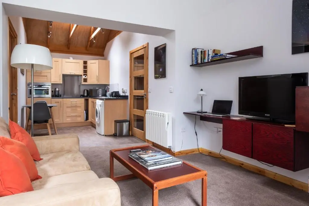 a living room with a couch and a tv and a table at Contemporary One Bedroom Apartment Close To All Amenities In Conservation Area in Tain