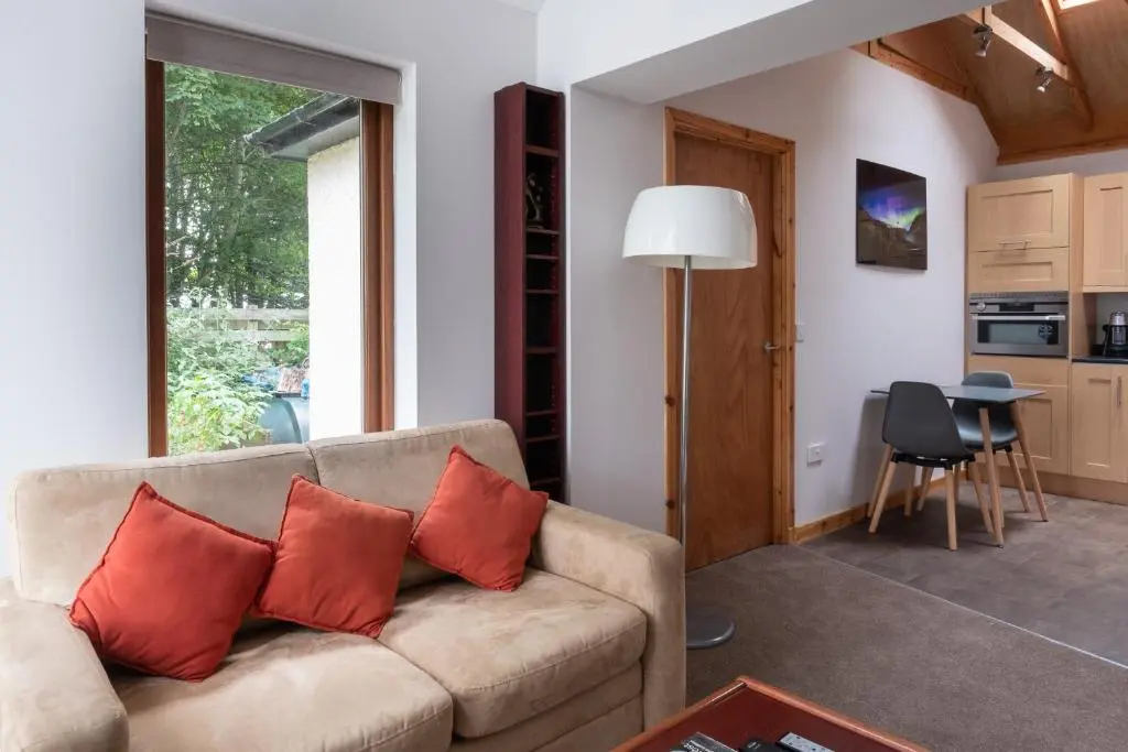 a living room with a couch with two red pillows at Contemporary One Bedroom Apartment Close To All Amenities In Conservation Area in Tain