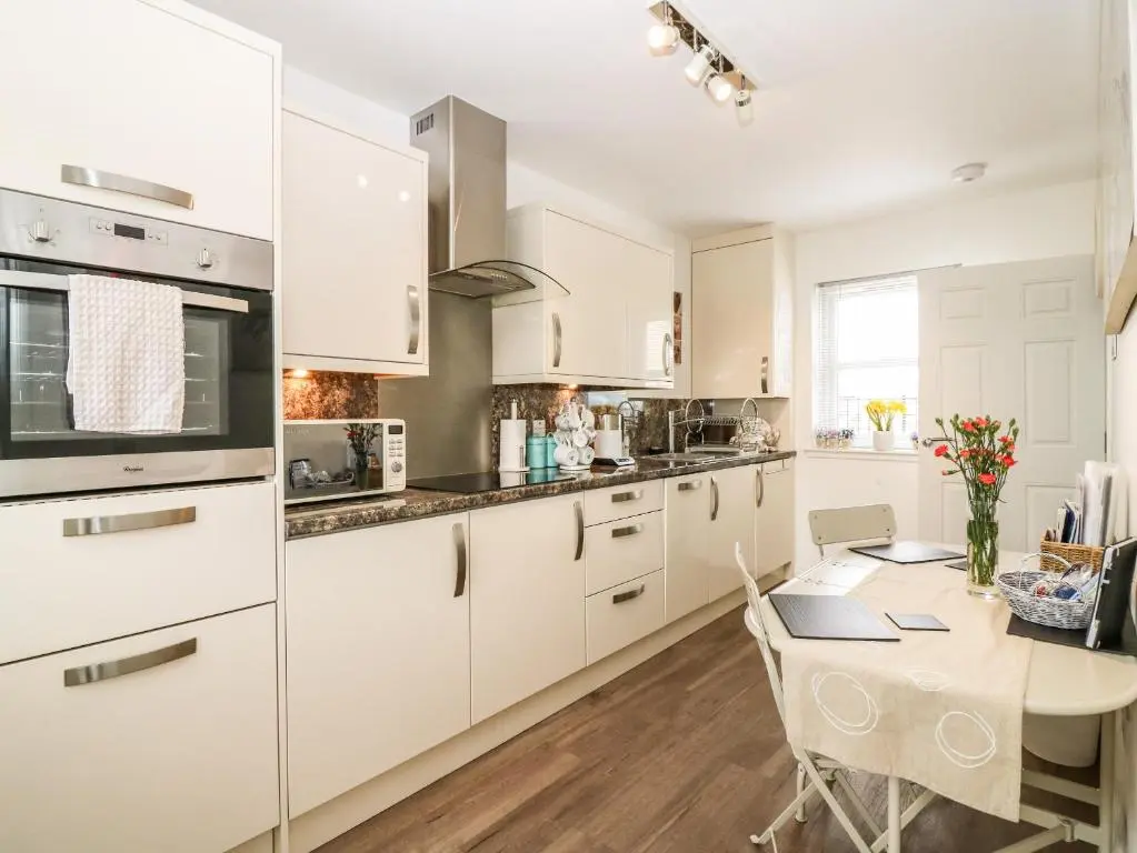 a kitchen with white cabinets and a table with a laptop at 38 The Views in Elgin