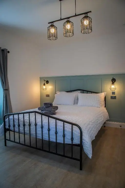 a bedroom with a large bed with two lights on it at Great Glen Way Canal Side Apartment in Inverness