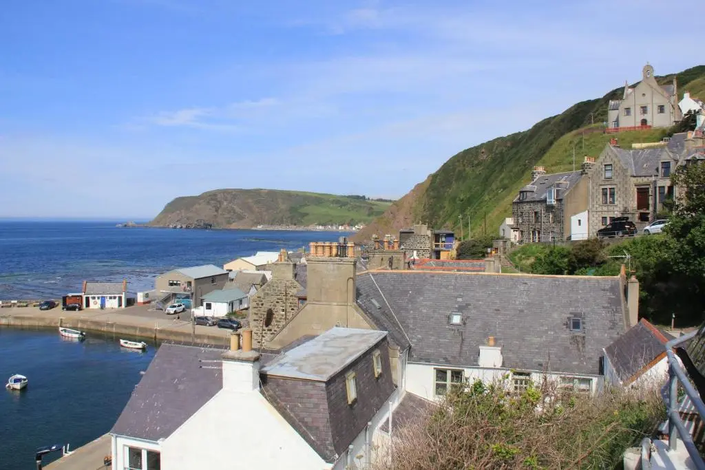 a group of houses on a hill next to the water at Bellevue Holiday Cottage in Gardenstown
