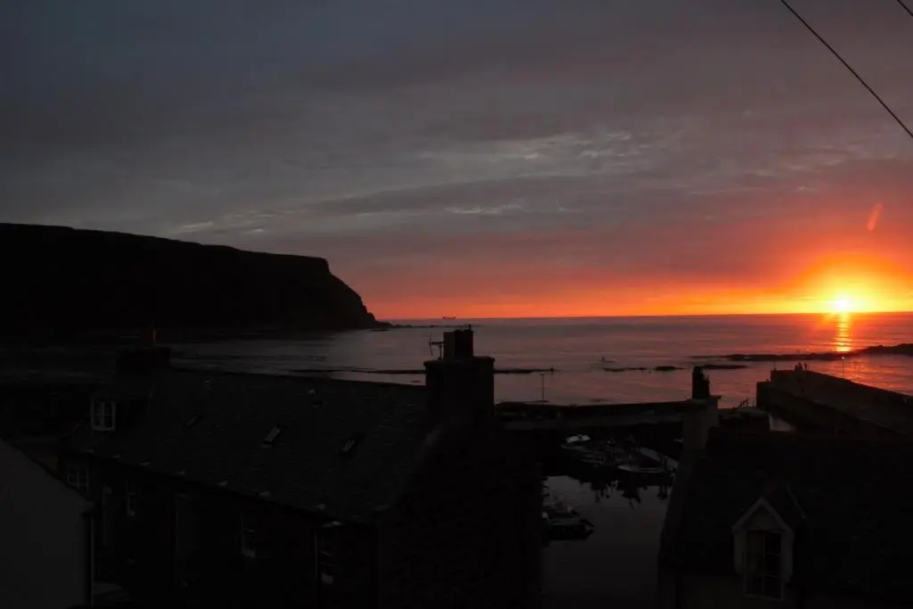 a sunset over the ocean with the sun in the sky at Bellevue Holiday Cottage in Gardenstown