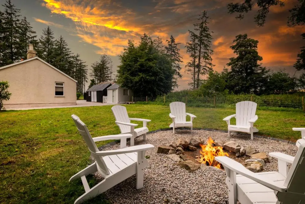 a group of white chairs around a fire pit at Stunning, Remodelled Cottage, Picturesque Location in Duncanston