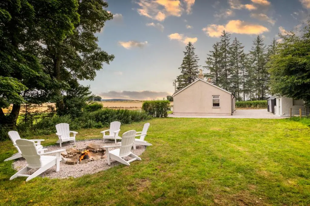 a group of white chairs sitting around a fire pit at Stunning, Remodelled Cottage, Picturesque Location in Duncanston