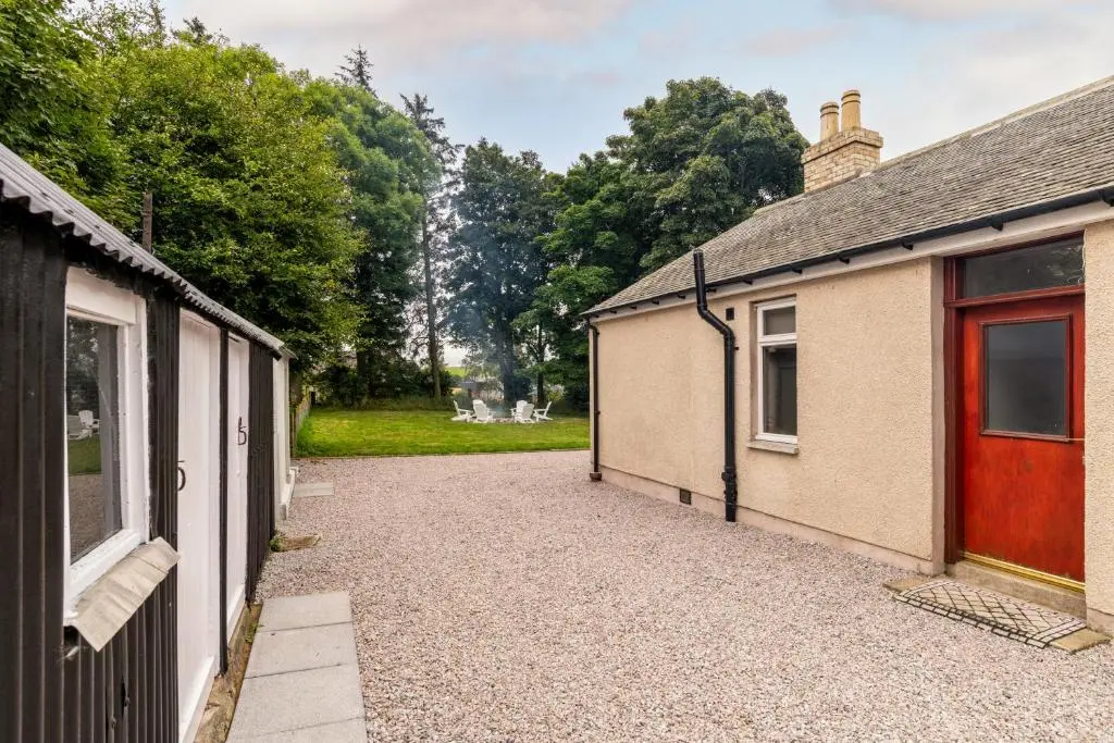 a driveway leading to a garage next to two buildings at Stunning, Remodelled Cottage, Picturesque Location in Duncanston