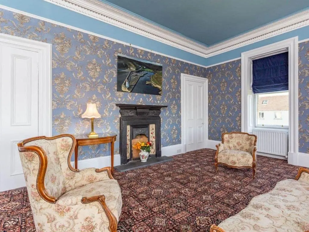 a living room with a fireplace and a couch and chairs at North Bank House in Lybster