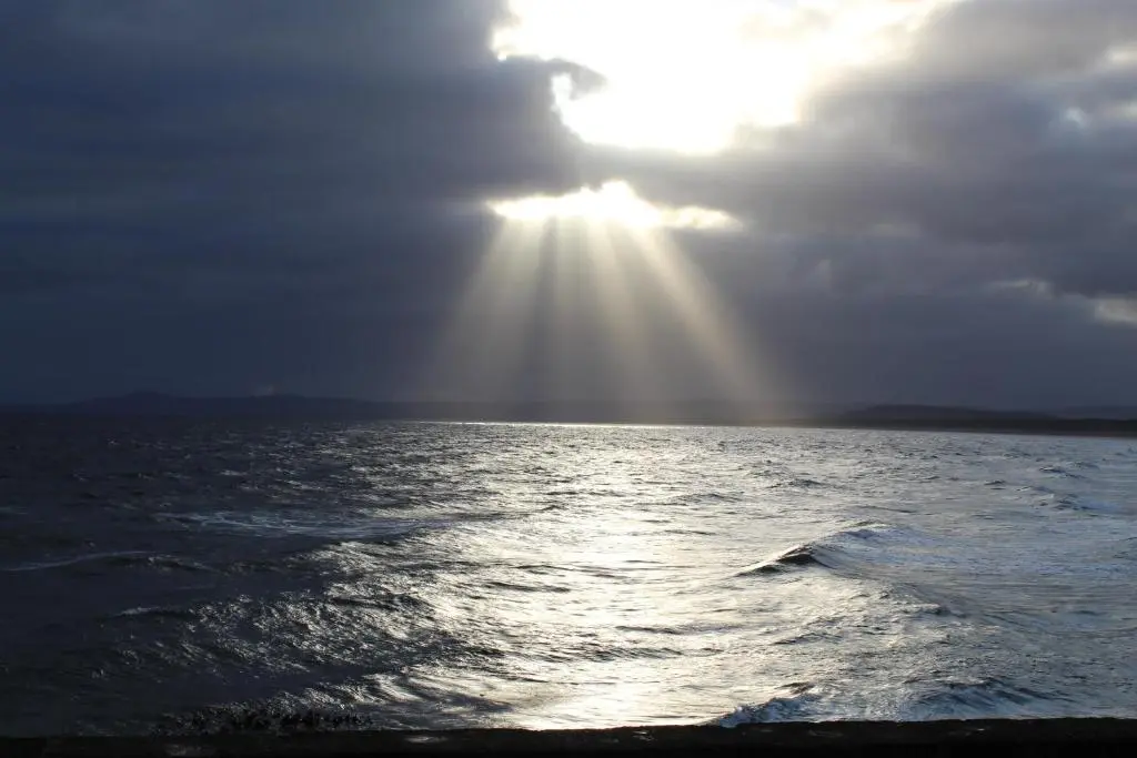 a sun shining through the clouds over the ocean at Beachfront Panoramic Seaview Free Wifi & Parking in Lossiemouth