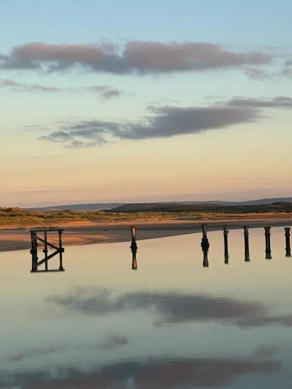 a woman standing in the water at sunset at Beachfront Panoramic Seaview Free Wifi & Parking in Lossiemouth