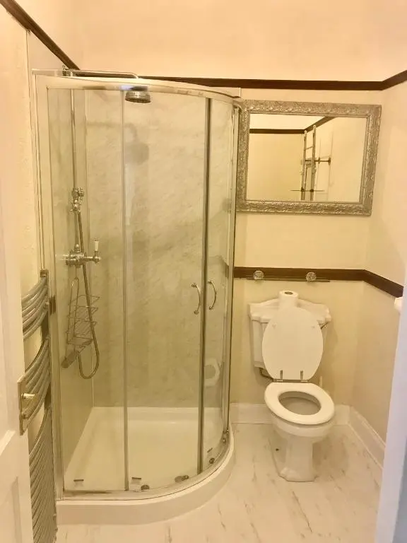 a bathroom with a shower with a toilet and a mirror at Cavell House in Inverness