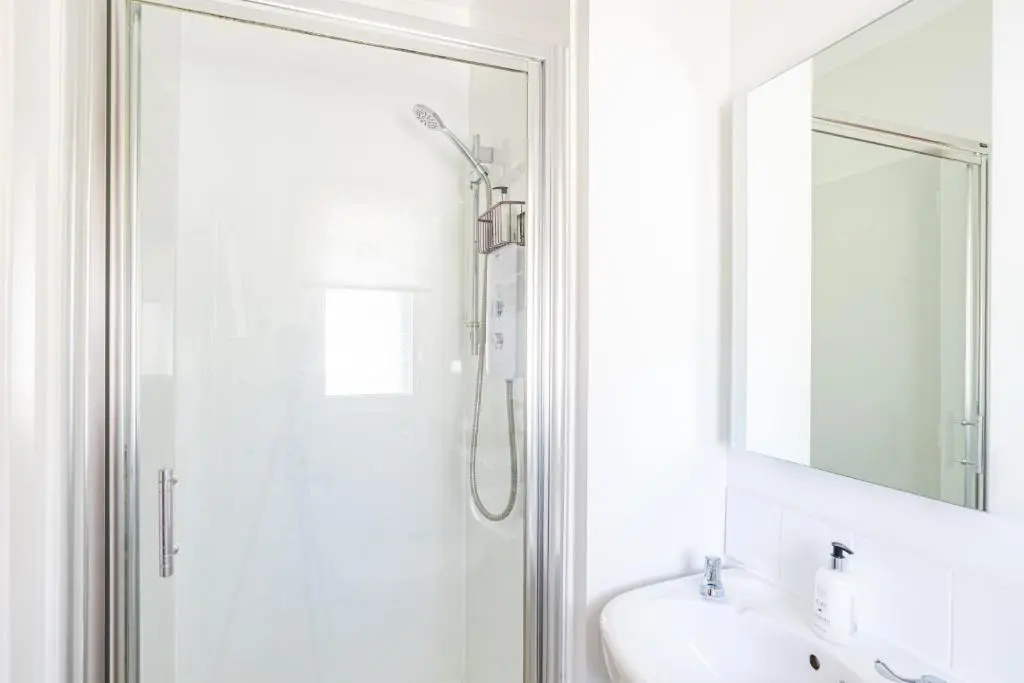 a bathroom with a shower and a sink and a mirror at Fern Lodge 2 with Hot Tub in Belladrum