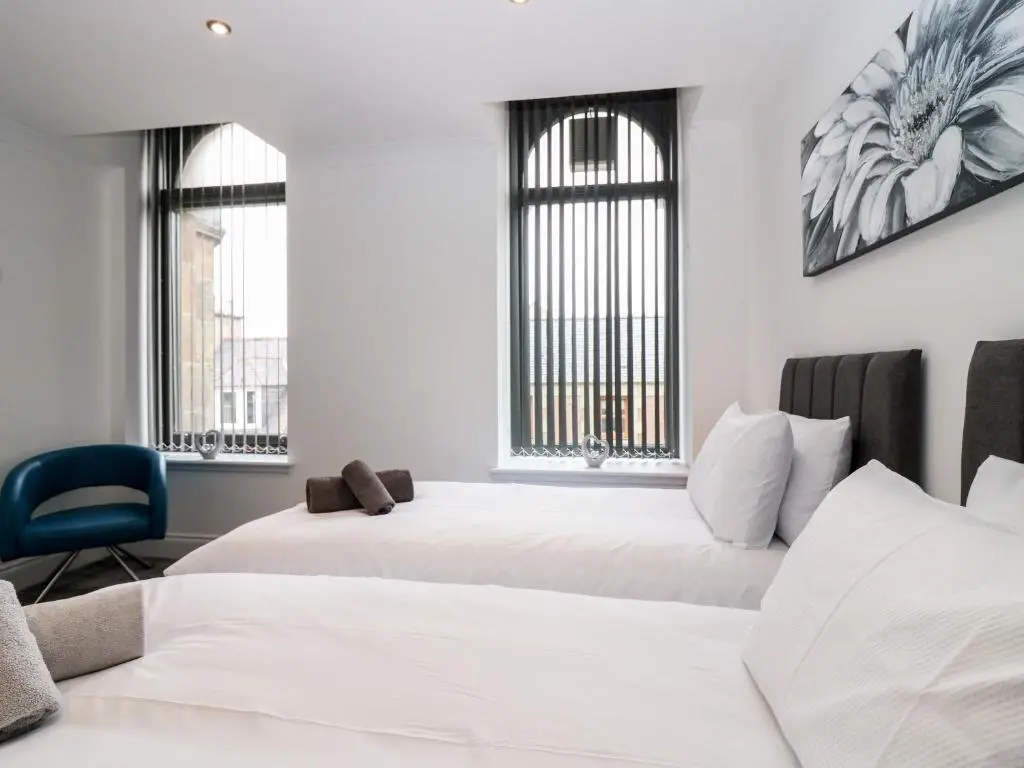 two beds in a room with two windows at The Clock Tower at The Institute Executive Apartments in Keith