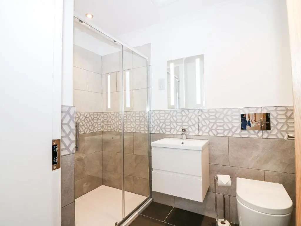 a bathroom with a toilet and a glass shower at The Keepers Cottage at The Institute Executive Apartments in Keith