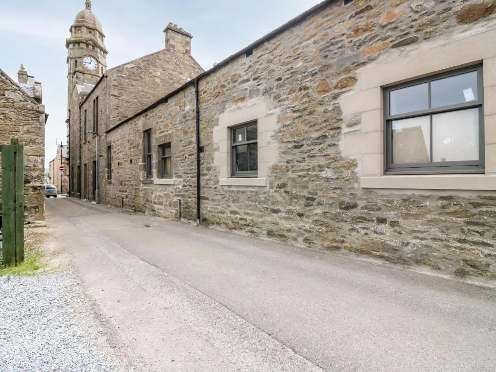 an old stone building with a window and a clock tower at The Keepers Cottage at The Institute Executive Apartments in Keith