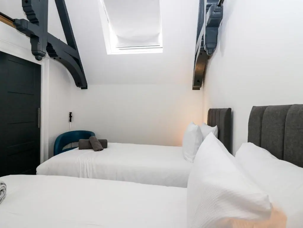 two beds in a room with white walls at The Court Room at The Institute Executive Apartments in Keith