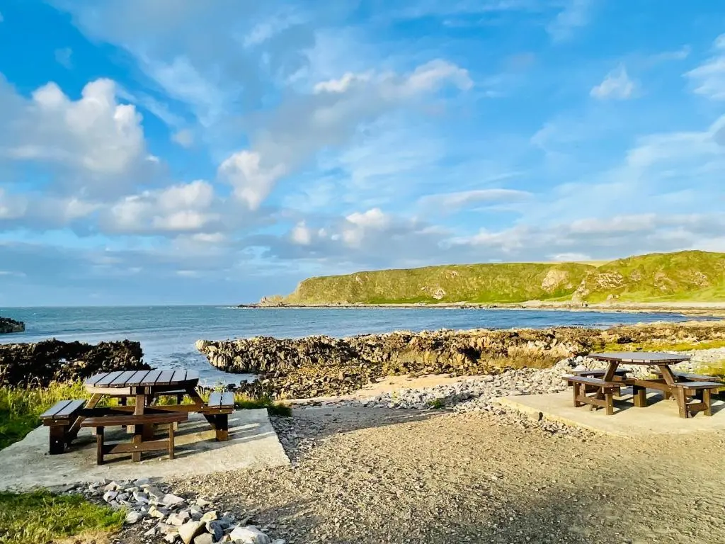 two picnic tables on a beach near the water at Spacious 2 Bedroom Home in Picturesque Cullen in Cullen