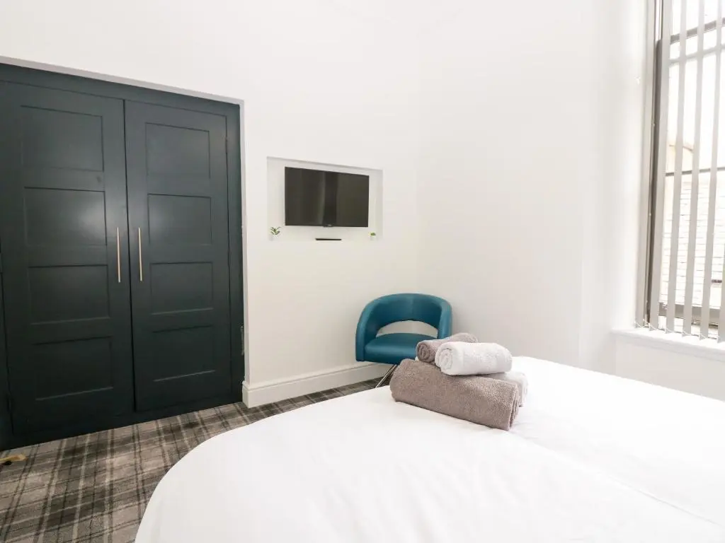 a bedroom with a bed and a blue chair at Council Chambers at The Institute Executive Apartments in Keith