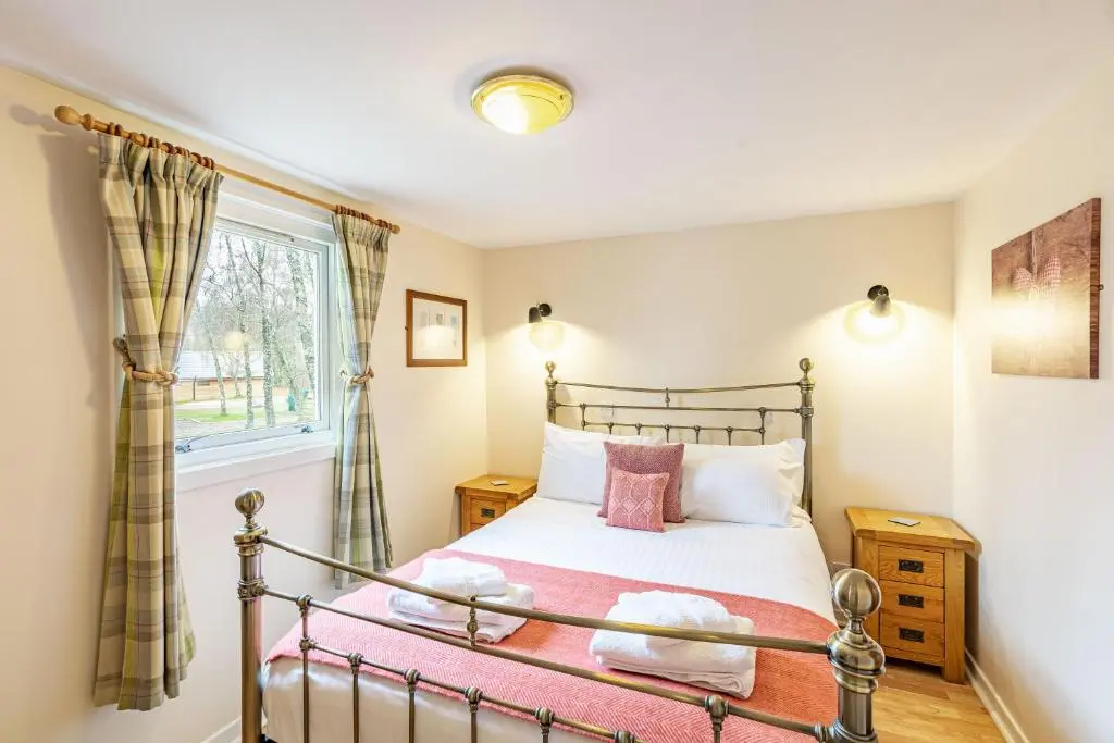 a bedroom with a bed and a window at Bracken Lodge 5 with Hot Tub in Belladrum