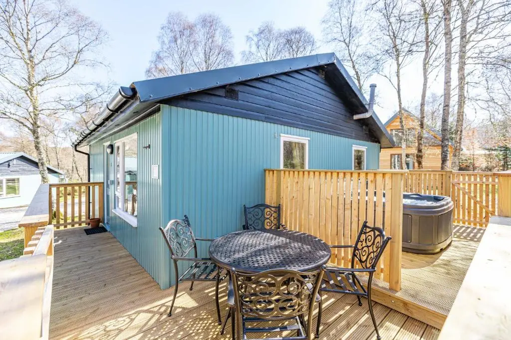 a tiny house with a table and chairs on a deck at Bracken Lodge 5 with Hot Tub in Belladrum