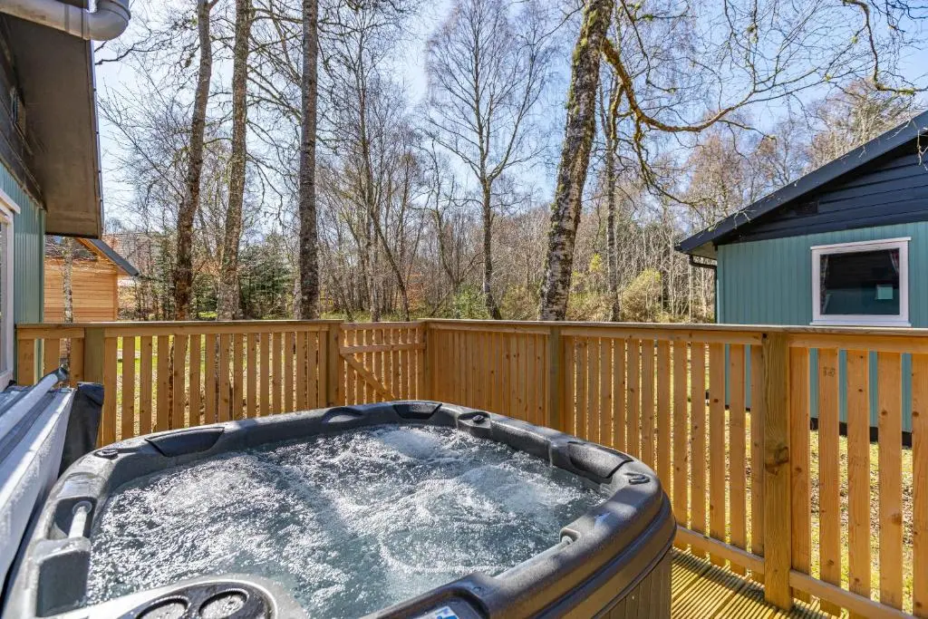 a hot tub on the deck of a house at Bracken Lodge 5 with Hot Tub in Belladrum